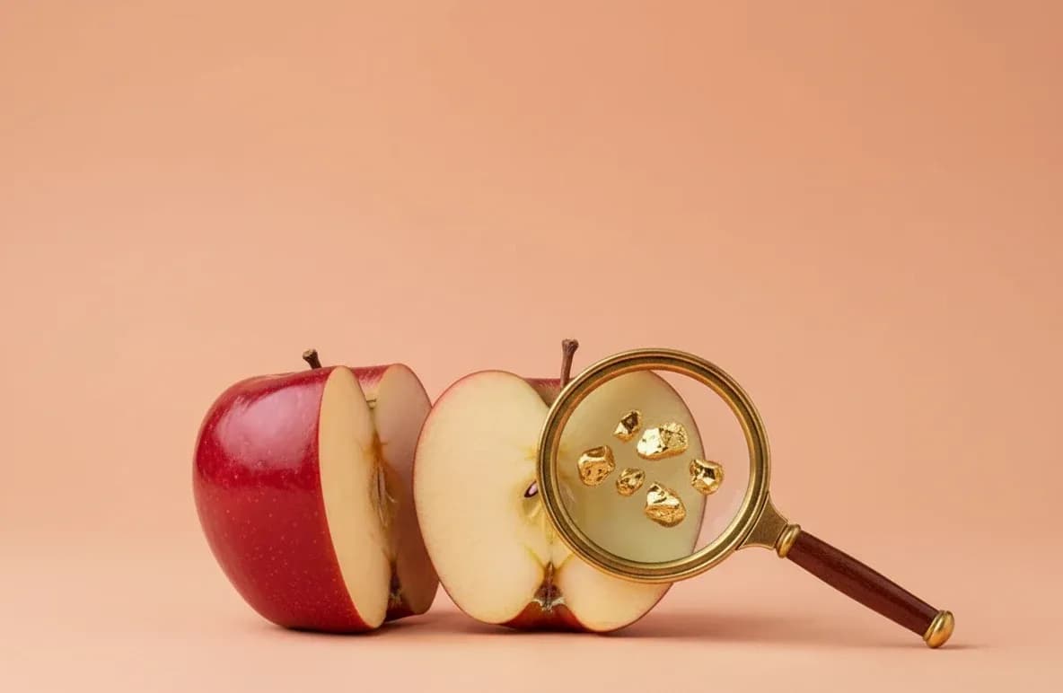 Halbierter Apfel, eine Lupe vergrößert den goldenen Kern (KI-generiert)